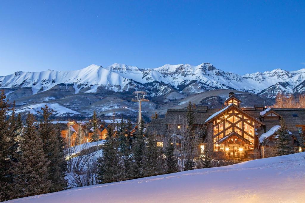 a house in the snow with mountains in the background at 2 BR Condominium - Luxury Skiin out - on River to0 in Telluride