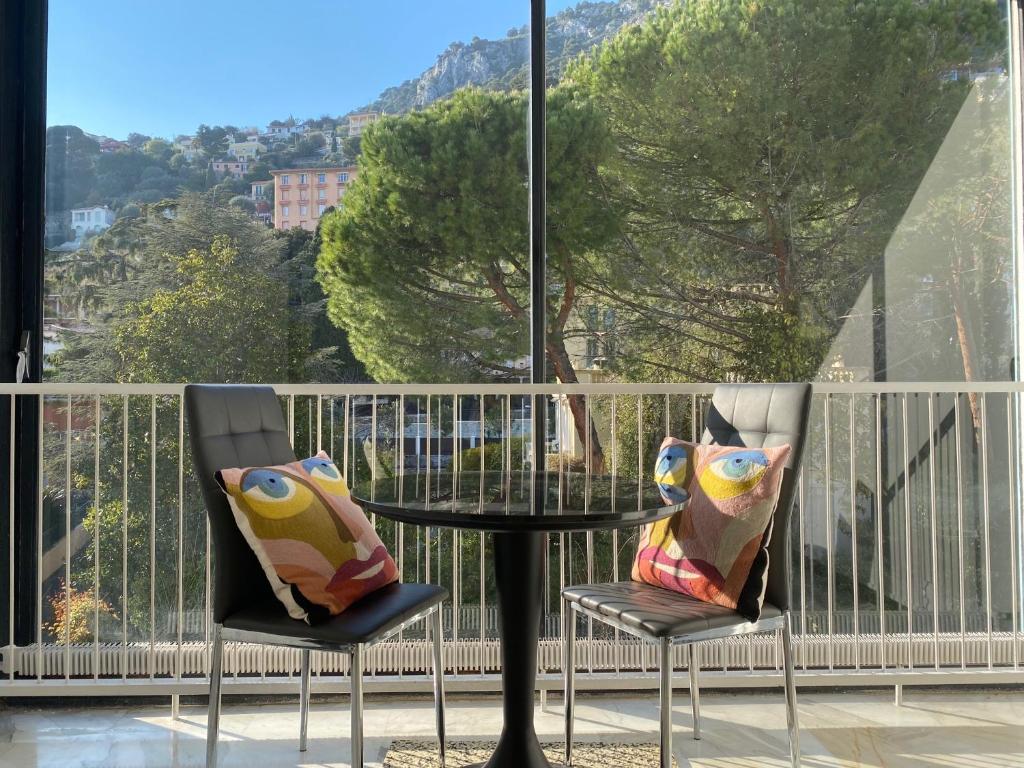 einen Tisch und zwei Stühle mit Kissen auf dem Balkon in der Unterkunft Beaulieu-sur-mer: appartement idéalement situé in Beaulieu-sur-Mer