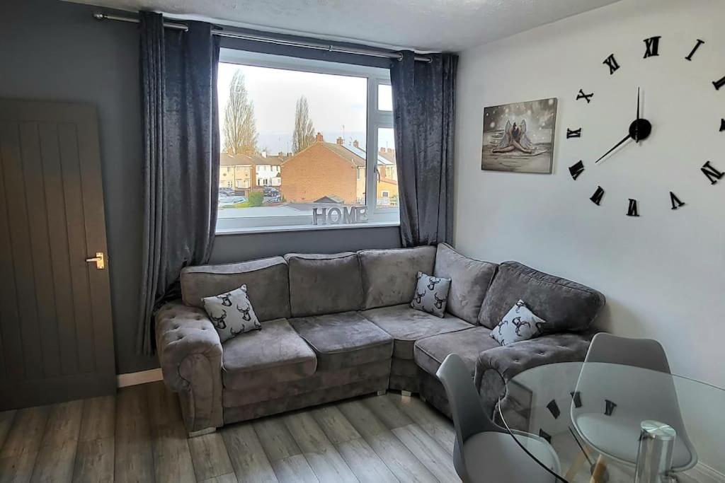 uma sala de estar com um sofá e um relógio na parede em Cosy 3 double bed flat sleeps 6 em Bedworth