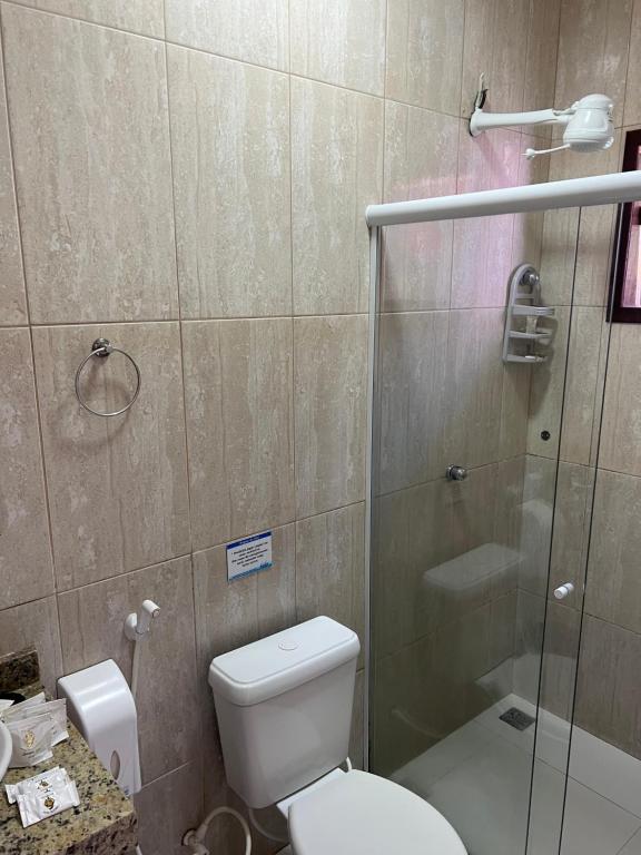 a bathroom with a toilet and a glass shower at Pousada Três Pescadores in Búzios