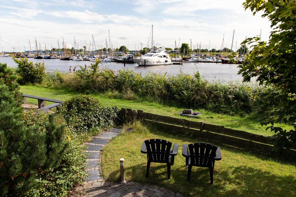 two chairs and a table in the grass near a marina at Havenzicht in Oostmahorn