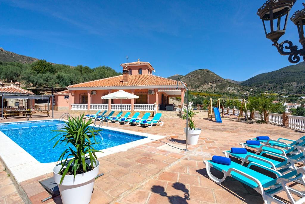 ein Pool mit blauen Liegestühlen und einem Haus in der Unterkunft Casa Los Cortijillos in Alcaucín