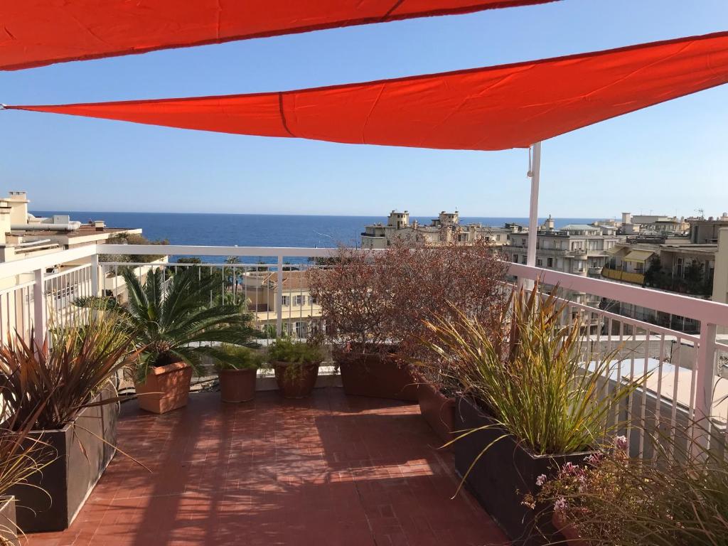 un balcon avec des plantes et un parasol rouge dans l'établissement LOFT 360° Nice, à Nice