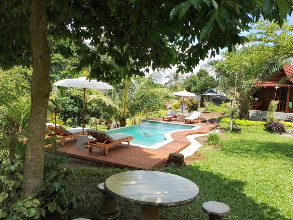 une arrière-cour avec une piscine, une table et des chaises dans l'établissement Bali Sesandan Garden, à Tabanan