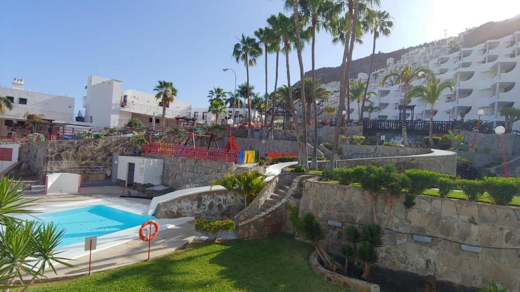 um resort com piscina e palmeiras em El Cardenal em Playa del Cura