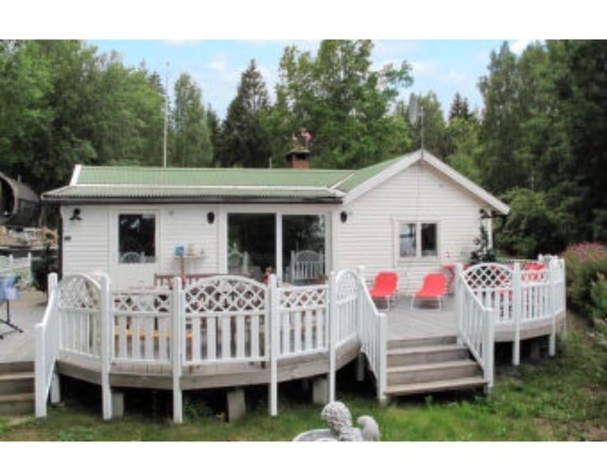 ein kleines Haus mit einer Veranda und einer Terrasse in der Unterkunft Modern stuga med sjöutsikt in Hammarby