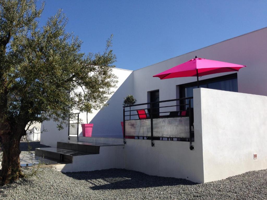 a white house with a pink umbrella and stairs at Maison Ocelia in Villeneuve-lès-Béziers