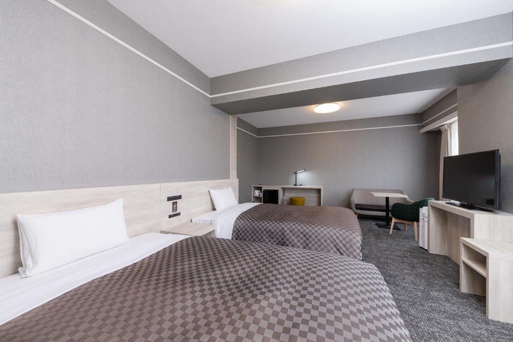 ein Hotelzimmer mit 2 Betten und einem Flachbild-TV in der Unterkunft The One Five Garden Kurashiki - Vacation STAY 96323v in Kurashiki
