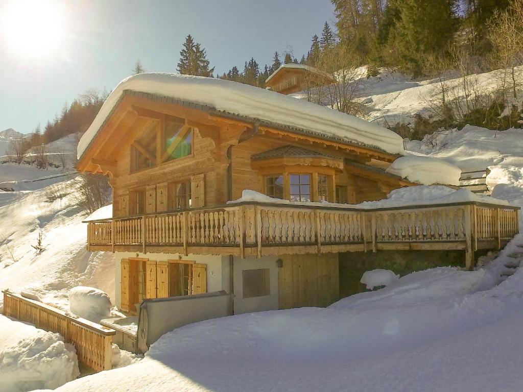 a log cabin in the snow with the sun behind it at Chalet Chocolat in La Tzoumaz