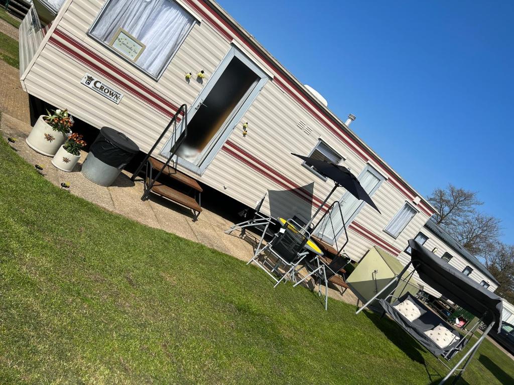 an rv parked in a yard with chairs and a grill at the Samanda Van Newport caravan park in Hemsby