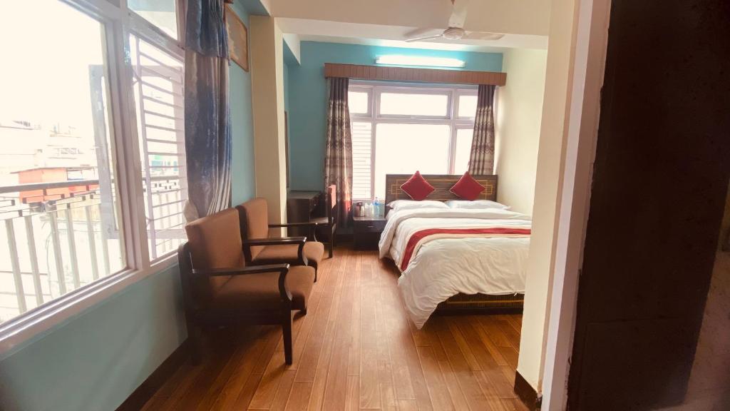 Hotel Discovery Inn في كاتماندو: غرفة نوم بسرير ونافذة وكرسي