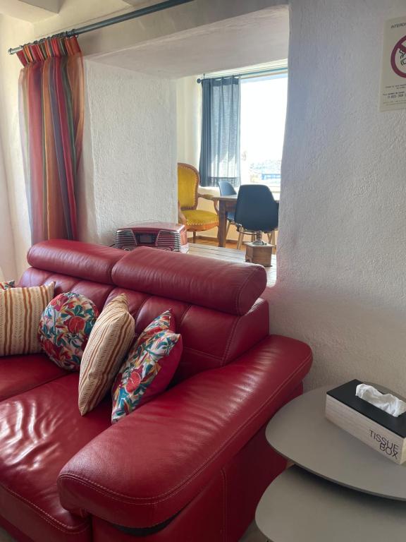 a red leather couch in a living room with a table at La Ferme l&#39;Etang in Vachères