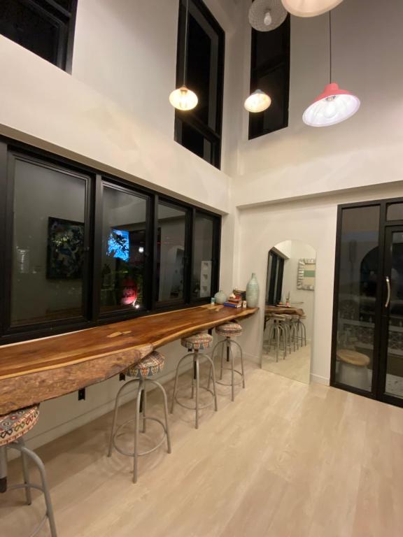 a bar with stools in a room with windows at Living Sage Chiang Mai - Boutique Art House in Chiang Mai