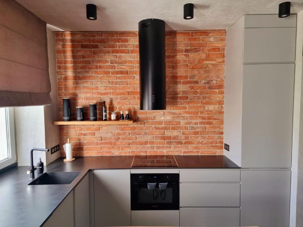 a kitchen with white cabinets and a brick wall at Luksusowy Apartament Przy Sądzie Toruń in Toruń