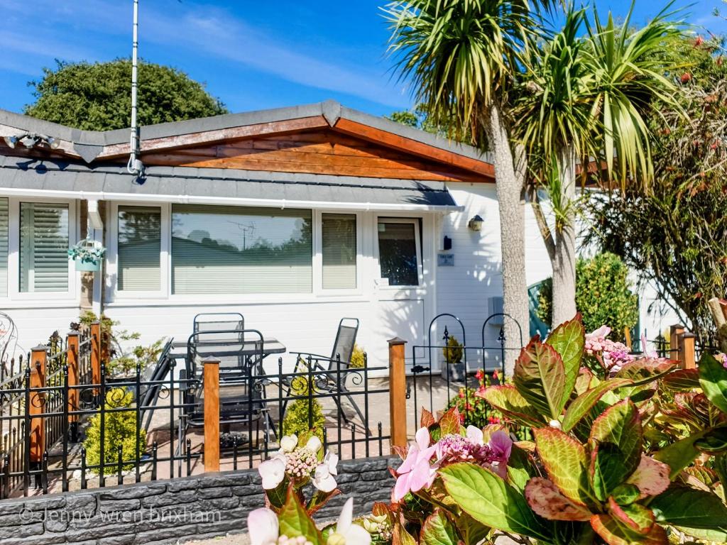 a white house with a fence and palm trees at Lucy Lou, charming holiday bungalow in Devon in Galmpton-on-the-Dart