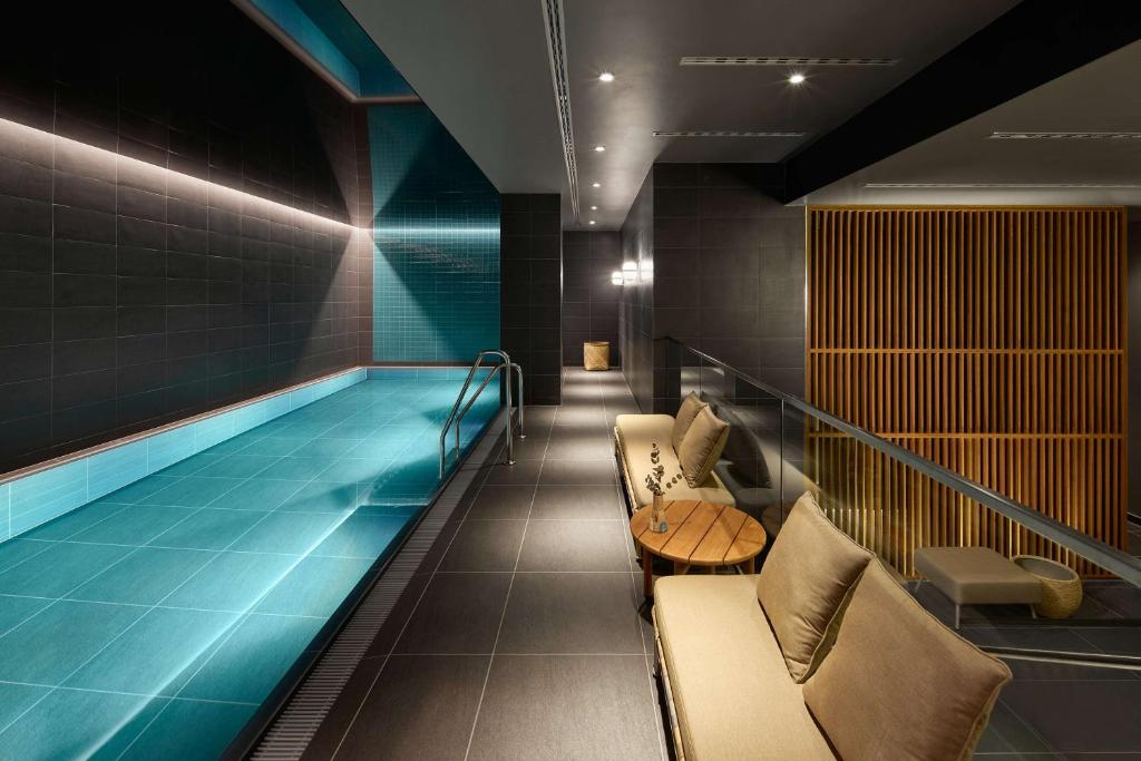 a swimming pool in a building with chairs and a couch at Adina Apartment Hotel Stuttgart in Stuttgart