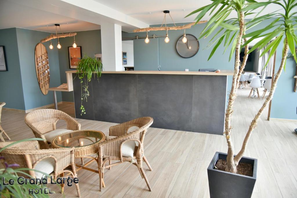 un comedor con mesa, sillas y una palmera en hôtel Le Grand Large, en Gruissan