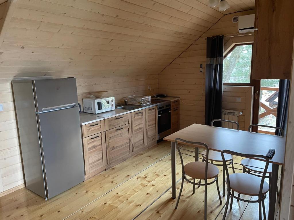 a kitchen with a refrigerator and a table and chairs at Sosnowy Domek Piętro in Graboszyce