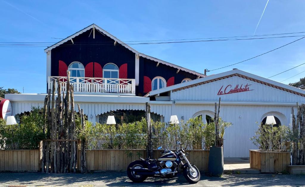 una motocicleta estacionada frente a un edificio en Hôtel Le Caillebotis en Cap-Ferret