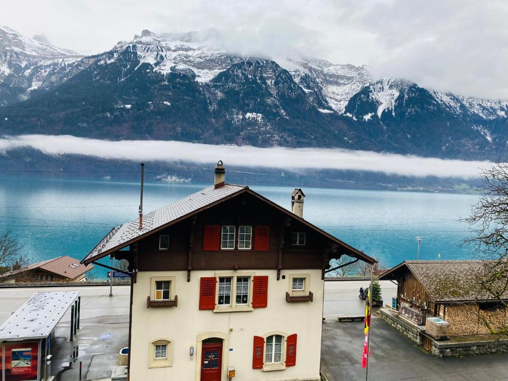 a house with red shutters and a lake and mountains at LakeSide Villa - 18 in Niederried