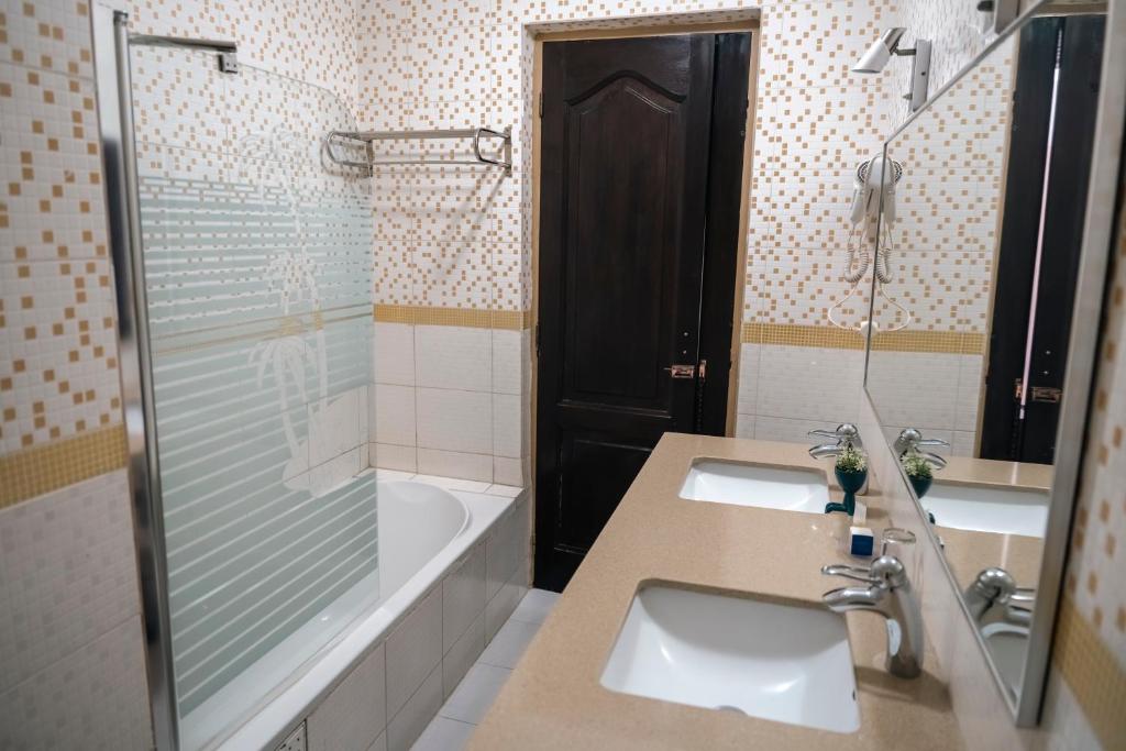 a bathroom with two sinks and a shower and a tub at Hotel Nina in Dakar