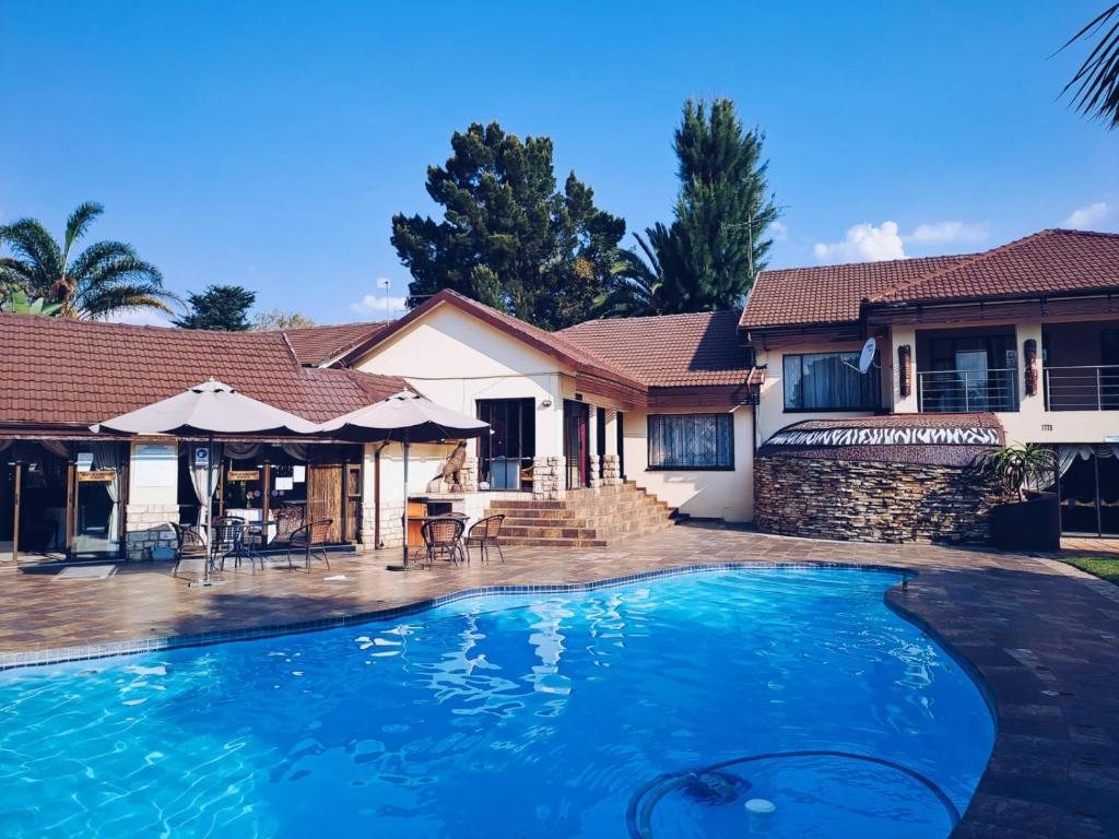 a swimming pool in front of a house at Ecotel Premier Lodge & Conference Centre in Benoni