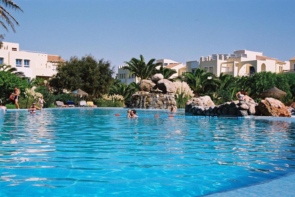 una piscina en un complejo con gente en el agua en Apartamentos Moguima, en Roquetas de Mar