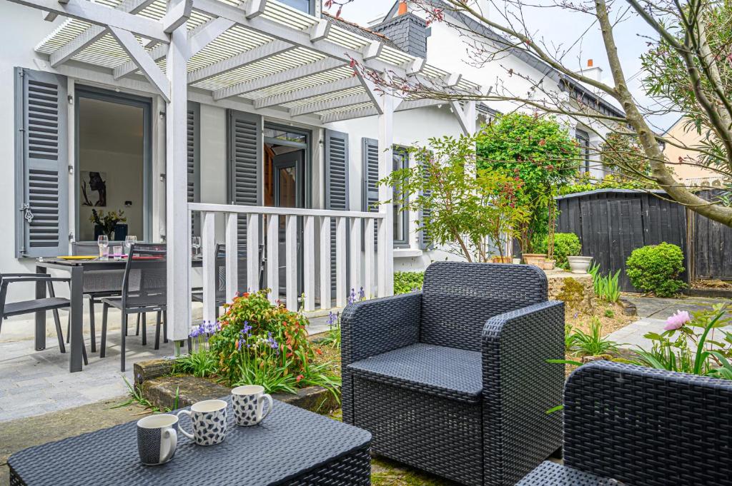 een patio met 2 stoelen, een tafel en een pergola bij Imagine - Charmante maison avec jardin in Vannes
