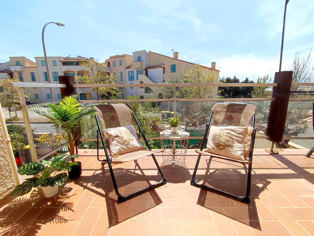 a patio with two chairs and a table on a balcony at Casa Flamingo - Appartement calme et moderne - 4 - in Canet-en-Roussillon