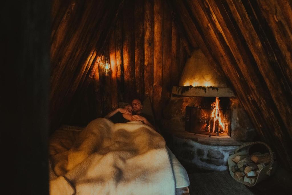 a man laying in bed in front of a fireplace at Attla Skogsby in MÃ¥nsarp