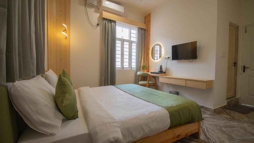 une chambre d'hôtel avec un lit et une télévision dans l'établissement Around Stays Hostel Rishikesh, Tapovan, à Rishikesh