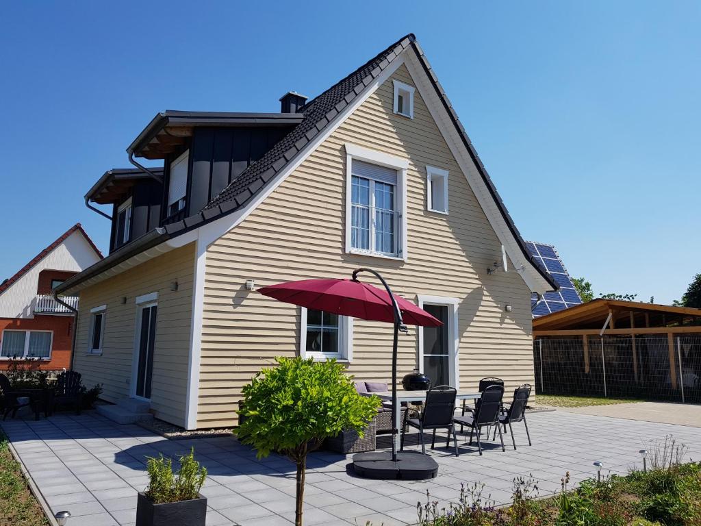 a house with a table and chairs and a red umbrella at Ferienhaus Frieda in Rechlin