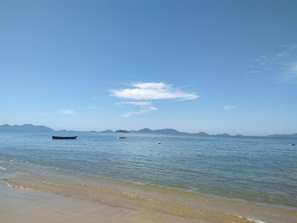 una playa con un barco en el agua en Pousada e restaurante Renascer en Mangaratiba