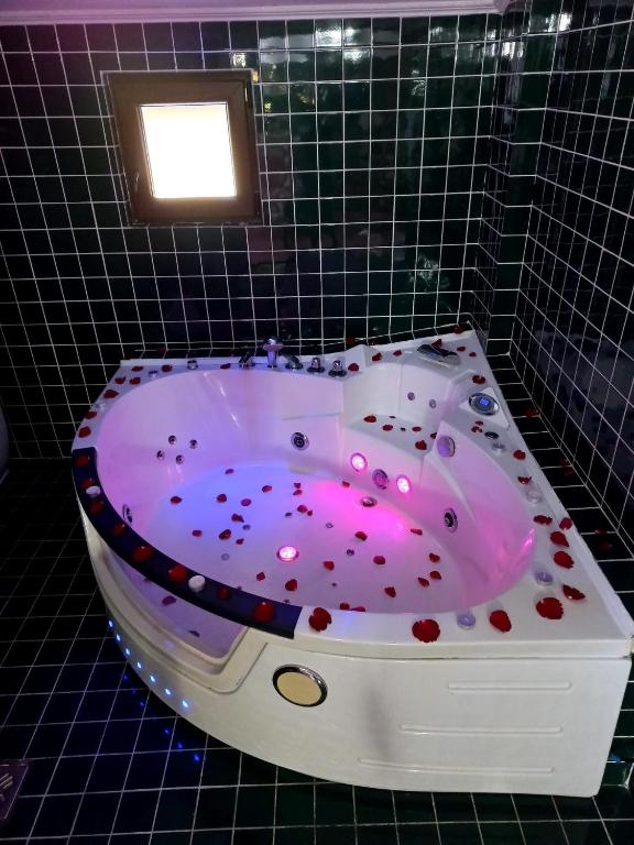 a bath tub in a tiled bathroom with pink lighting at Pensiunea La Busu in Bran