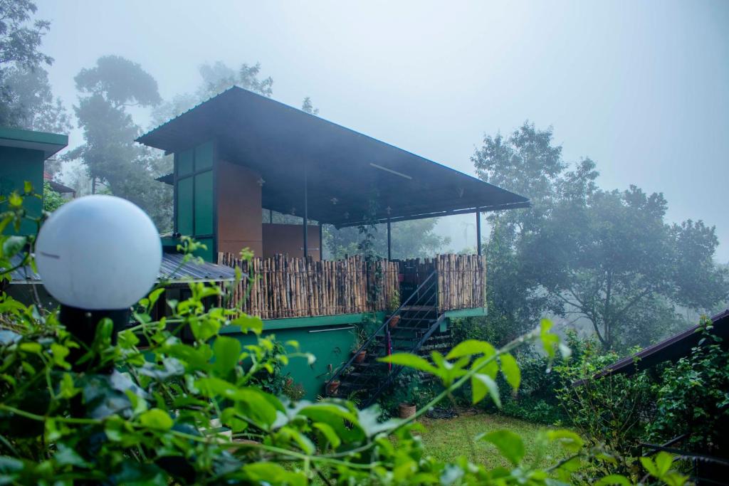 a small house with a porch and a fence at Edens Munnar in Munnar