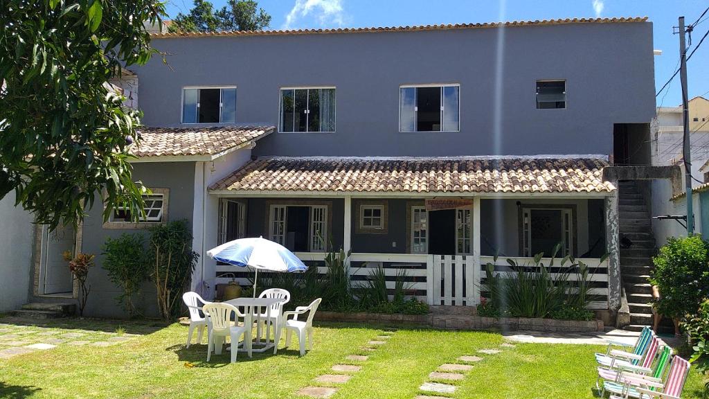 une maison avec une table, des chaises et un parasol dans l'établissement CASA DE FÉRIAS PRAIANA, à Cabo Frio