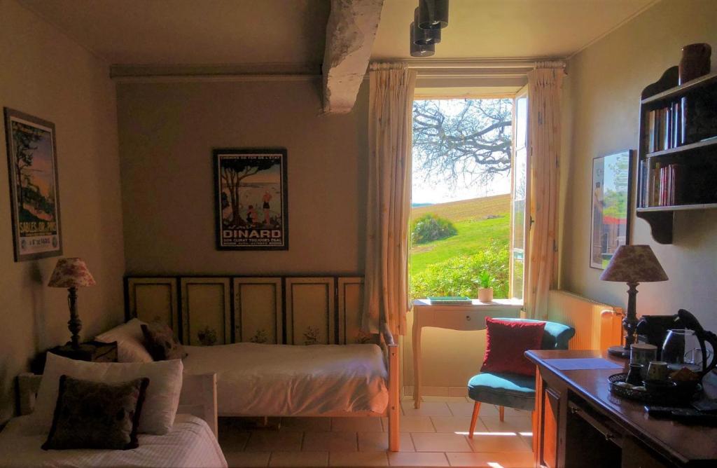 a bedroom with a bed and a window and a chair at Maison Lamothe in Flamarens