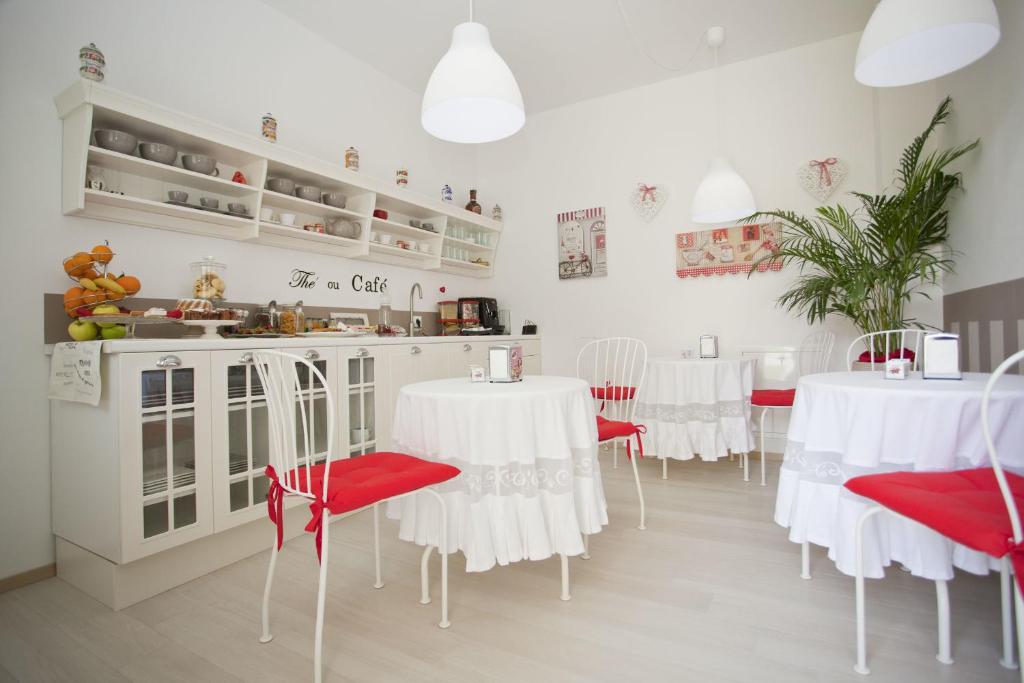 a dining room with white tables and red chairs at Dimora delle Emme in Ravenna