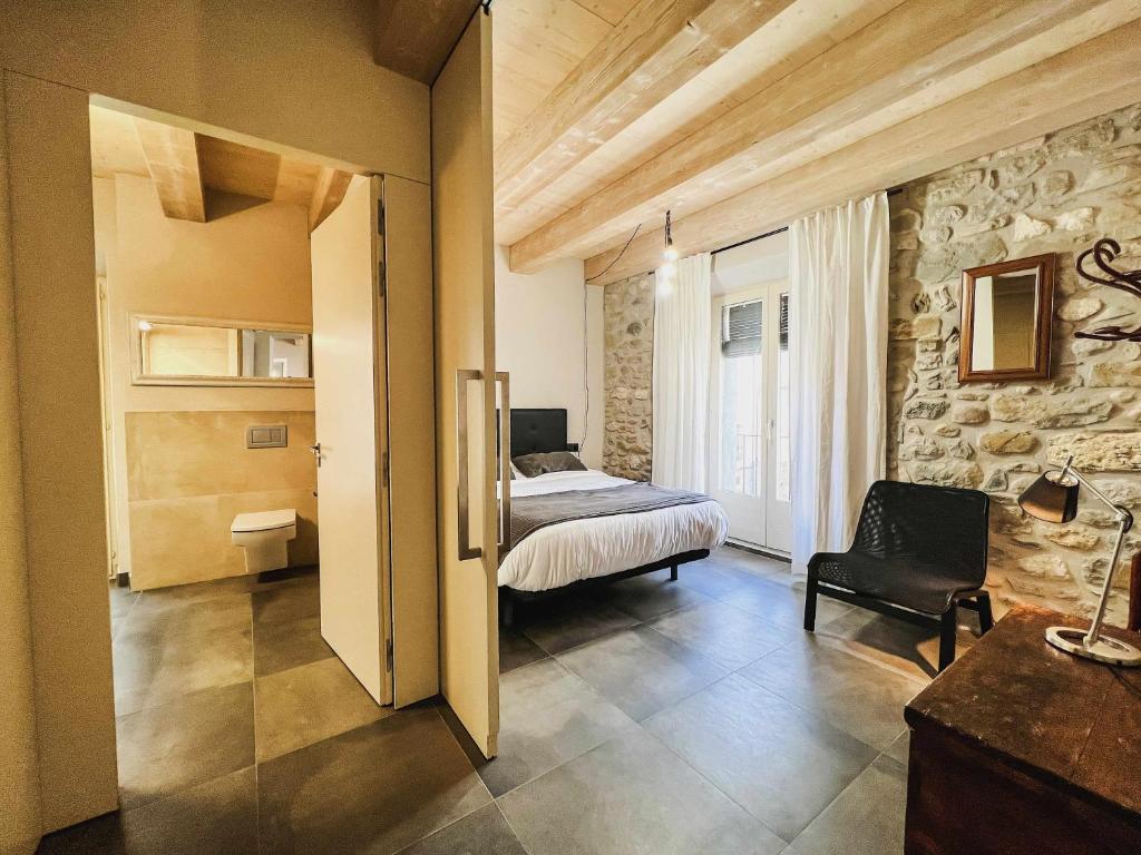 ein Schlafzimmer mit einem Bett und einer Steinmauer in der Unterkunft El Call LEstudi en la judería de Besalú in Besalú