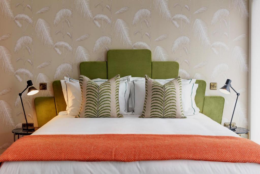 ein Bett mit einer orangefarbenen Decke und weißen Kissen in der Unterkunft Brama in Bromley