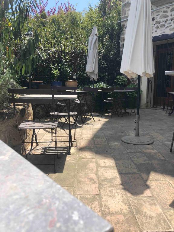 a patio with a table and an umbrella and chairs at Au bout du pré in Pézenas