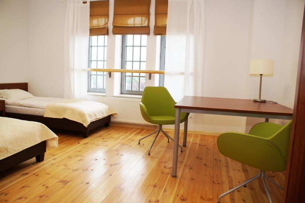 een slaapkamer met een bureau en een bed en een tafel en stoelen bij Hostel Międzynarodowe Centrum Spotkań Młodzieży in Toruń