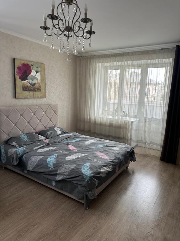 Schlafzimmer mit einem Bett und einem Kronleuchter in der Unterkunft ВІП квартира в новобудові в центрі міста in Riwne