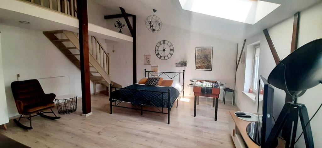 a living room with a bed and a table and stairs at Attic Room Ełk in Ełk