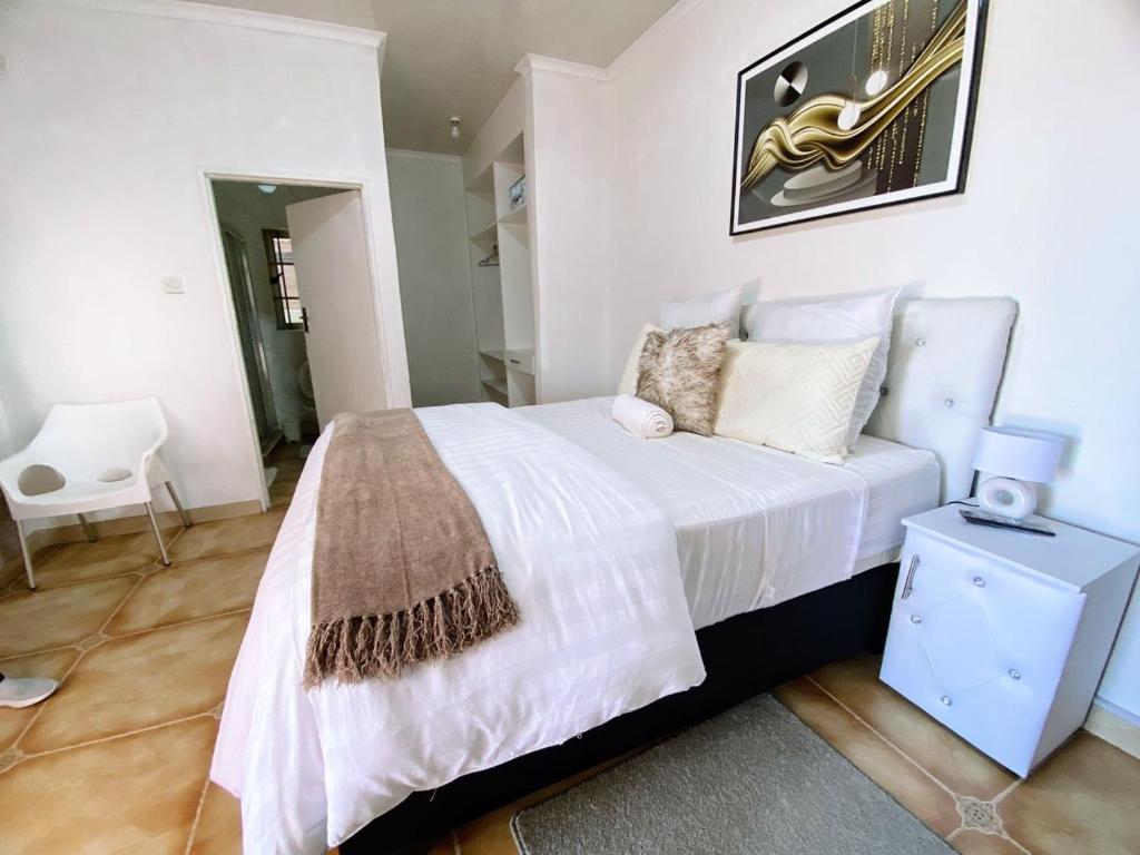1 dormitorio con 1 cama blanca grande con silla en Ranzi Court Guest House, en Palapye