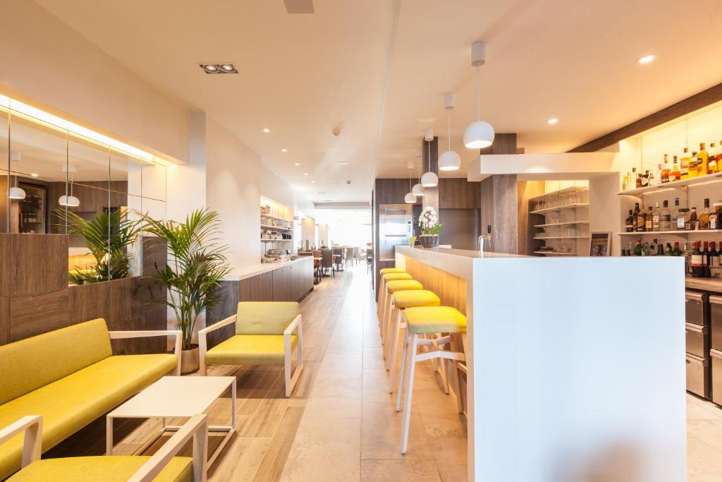 un restaurant avec des chaises jaunes et un bar dans l'établissement Hotel Les Mouettes, à Wenduine