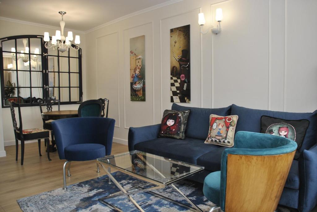 un soggiorno con divano blu e sedie di Lustrzany Skwer a Gdynia