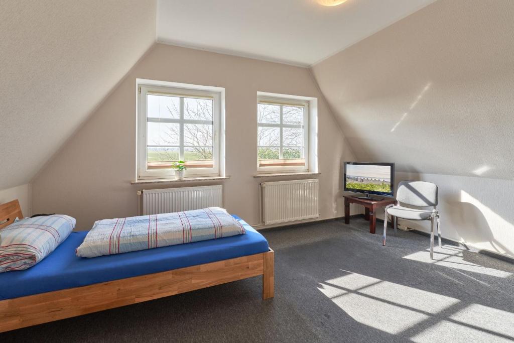 a bedroom with a bed and a desk and windows at Vosskuhl Kabuff Dree in Südermarsch