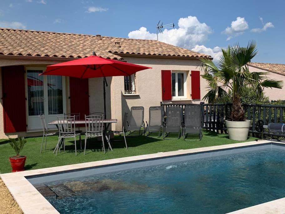 une maison avec une table et un parasol à côté d'une piscine dans l'établissement Villa sud de la France avec piscine privée, à Les Fumades-Les Bains