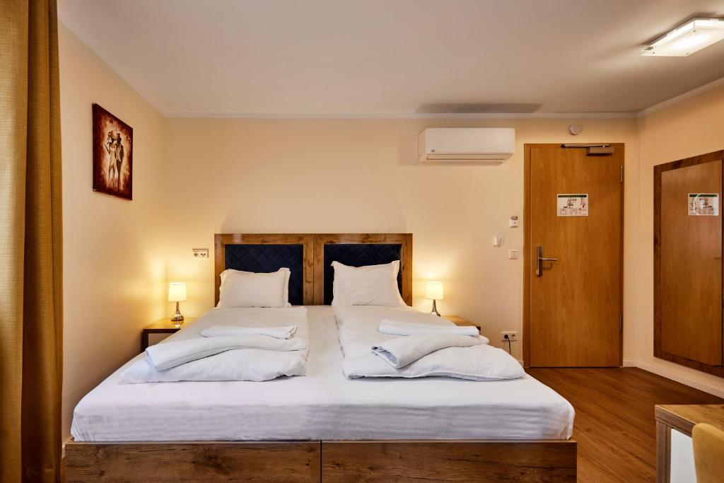1 dormitorio con 1 cama grande con sábanas y almohadas blancas en Hotel Isha, en Frankfurt